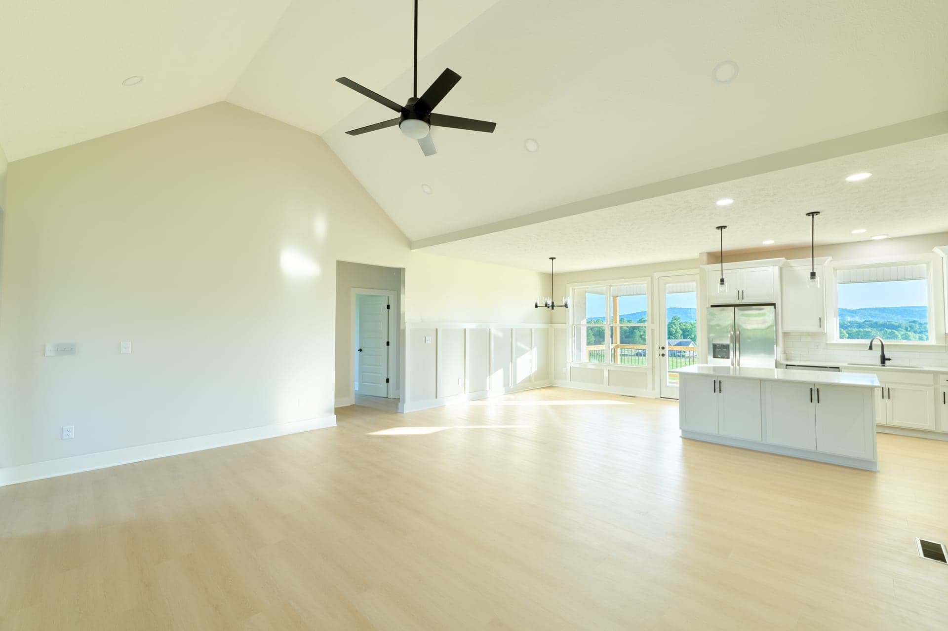 An empty great room and kitchen illuminated by natural light